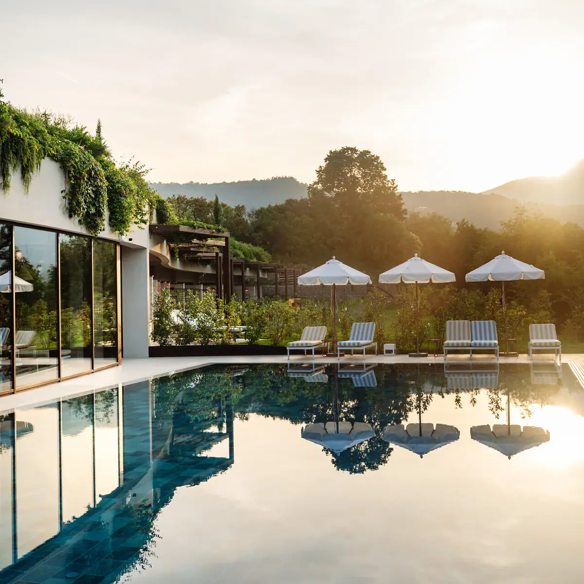 Ein Pool mit Liegestühlen und Sonnenschirmen vor einem Gebäude.