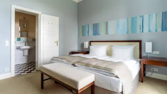 Ein Hotelzimmer mit blauer Tapete, einem großen Bett einem angrenzenden Badezimmer.