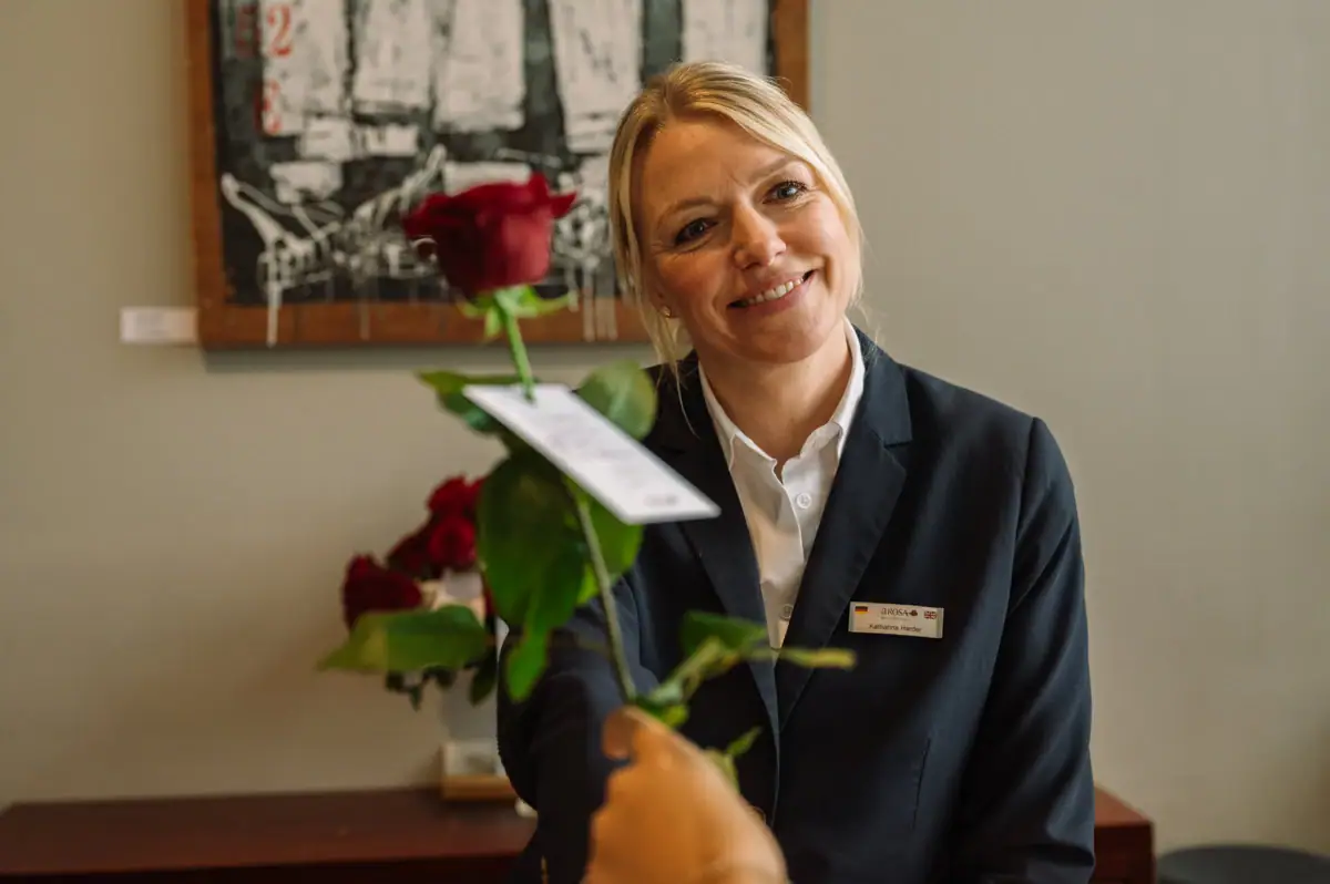 Eine Frau lächelt eine rote Rose an.