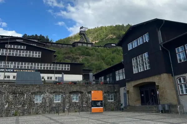 Ein Gebäude mit einem Hügel im Hintergrund und einem Bergwerk im Vordergrund.