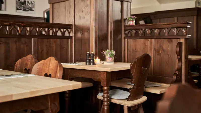 Ein Tisch mit Kerzen und Stühlen in einem Raum mit holzvertäfelten Wänden.