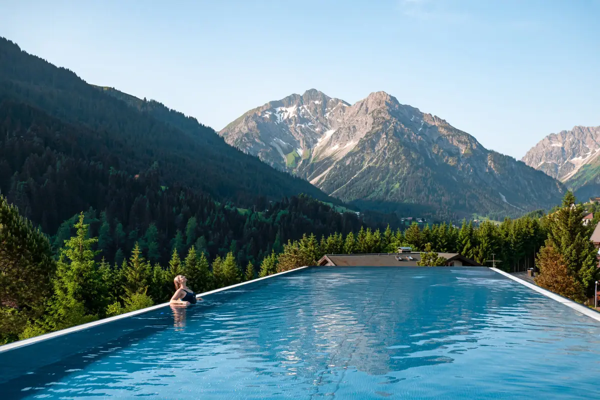 Eine Person in einem Pool mit Bergen im Hintergrund.