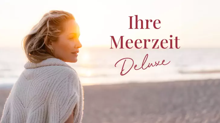 Eine Frau blickt entspannt über ihre Schulter, während sie an einem sonnigen Strand steht. Die goldene Stunde beleuchtet ihr Gesicht und ihren gestrickten Pullover. Der Text 'Ihre Meerzeit Deluxe' ist in Rot über dem Bild platziert.