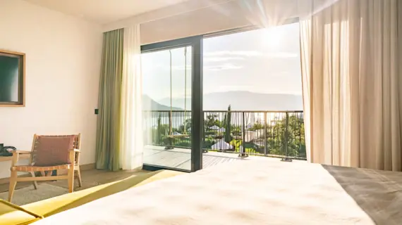 Hotelzimmer mit Bett und Balkon mit Seeblick.