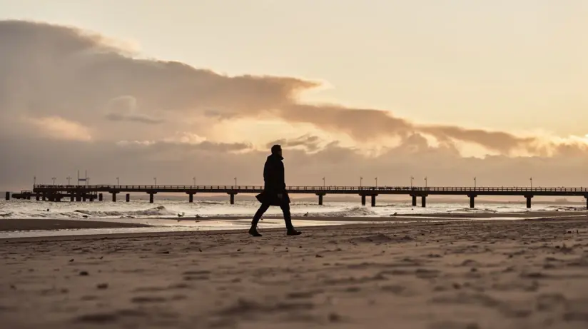 Person geht bei Sonnenuntergang am Strand entlang.