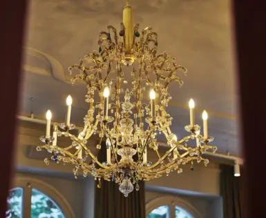 Detailaufnahme eines kunstvoll verzierten Kronleuchters mit funkelnden Kristallen und goldenen Elementen im eleganten Ambiente des Straubinger Grand Hotel in Bad Gastein.