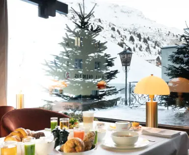 Ein appetitlich gedeckter Frühstückstisch mit Bill auf schneebedeckte Berge. 