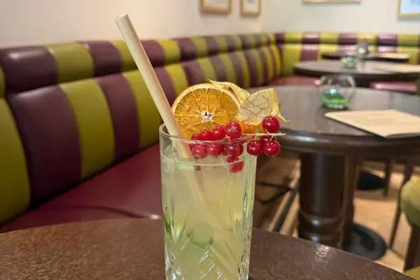 Ein Glas mit einem Cocktail und Früchten auf einem Tisch.