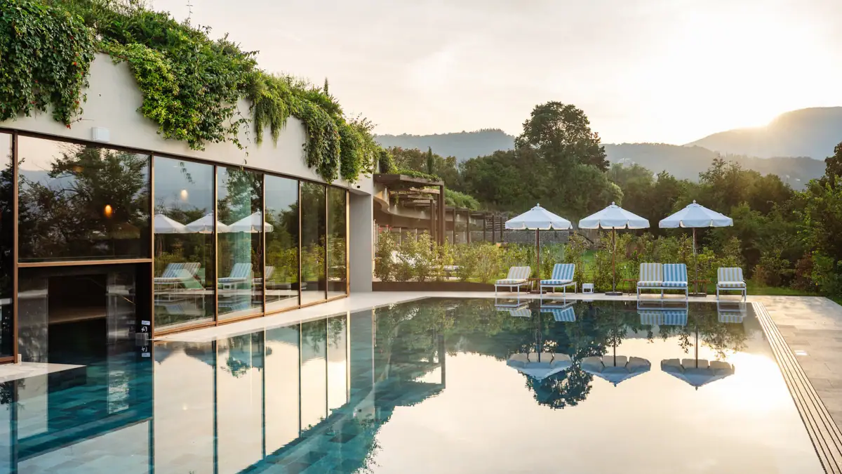 Ein Pool mit Liegestühlen und Sonnenschirmen vor einem Gebäude.