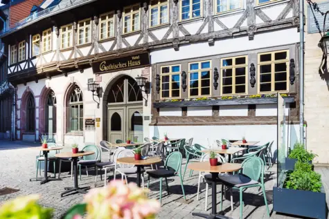 Eine Gruppe von Menschen sitzt an Tischen im Freien vor einem Gebäude.