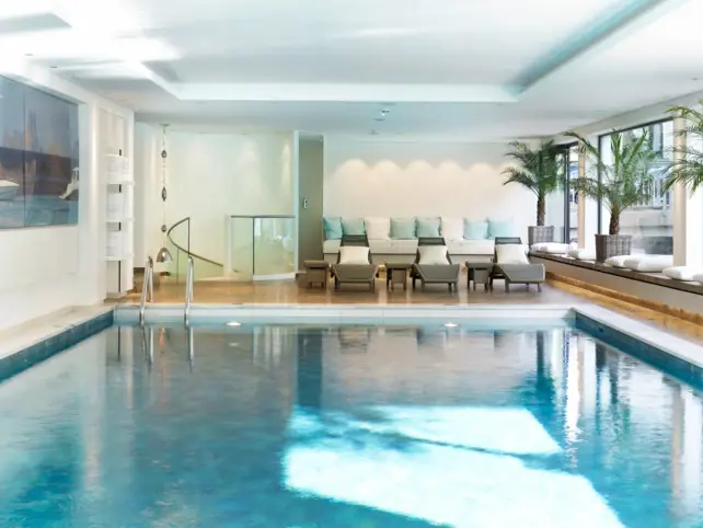 A large indoor pool with a few loungers in the background.