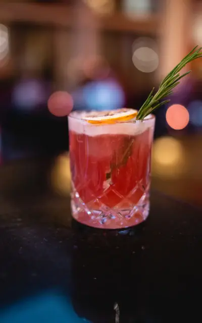 Ein Glas mit einem Getränk und einem Rosmarinzweig darauf.