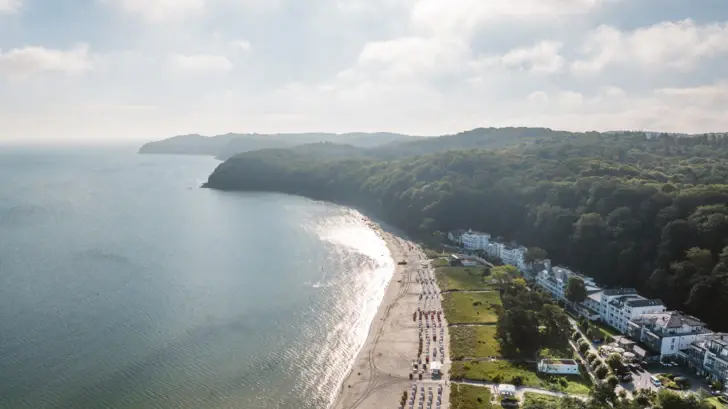 Luftaufnahme über die Ostseebucht Binz mit Meer, Ostseestrand und der ersten Hotelreihe im Blick