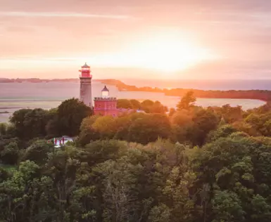  Eine Inselküste mit einem Leuchtturm bei Sonnenuntergang