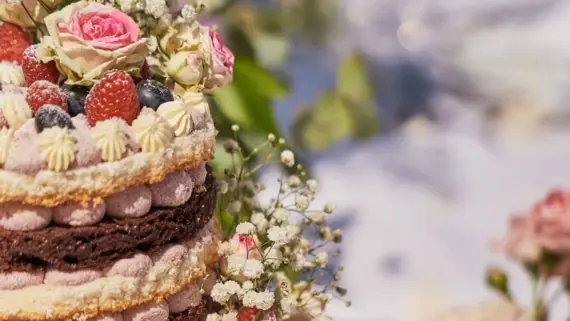 Eine köstlich angerichtete Hochzeitstorte mit einer Erdbeercreme, Früchten und Blumen. 