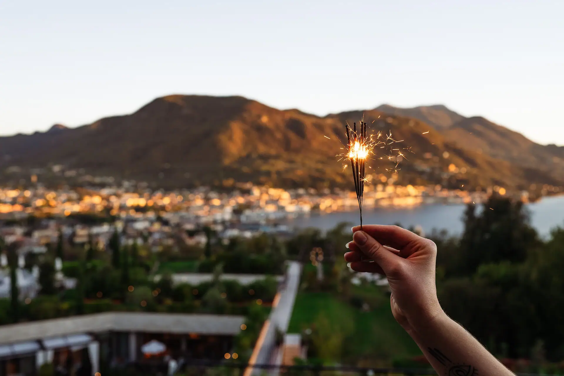 Eine Person hält eine Wunderkerze vor einem Berg im Hintergrund.