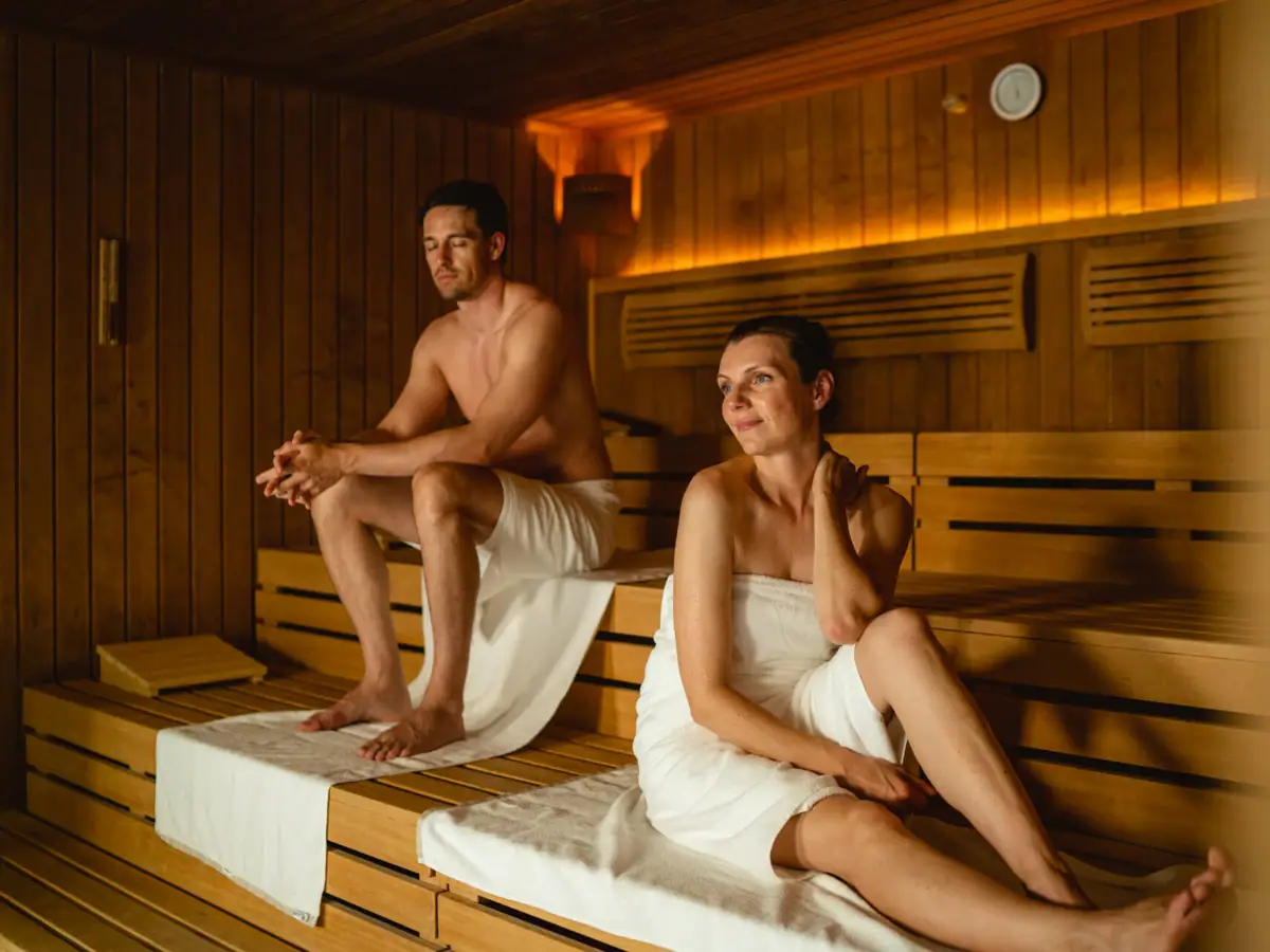 Ein Mann und eine Frau sitzen auf einer Bank in einer Sauna.