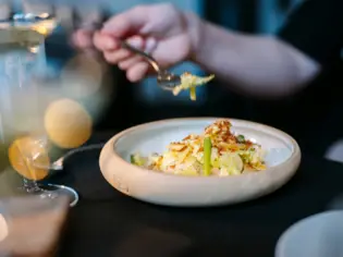 Person holding a fork over a plate of food in a restaurant.