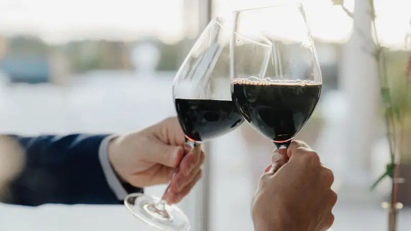 Zwei Hände halten Weingläser.