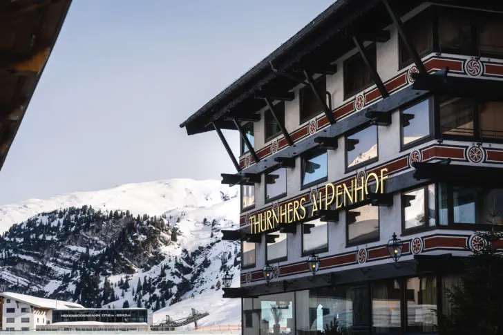 Gebäude mit Schild im Vordergrund, umgeben von Schnee und Bergen.