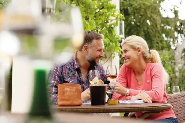 Ein Mann und eine Frau sitzen an einem Tisch mit Weingläsern.