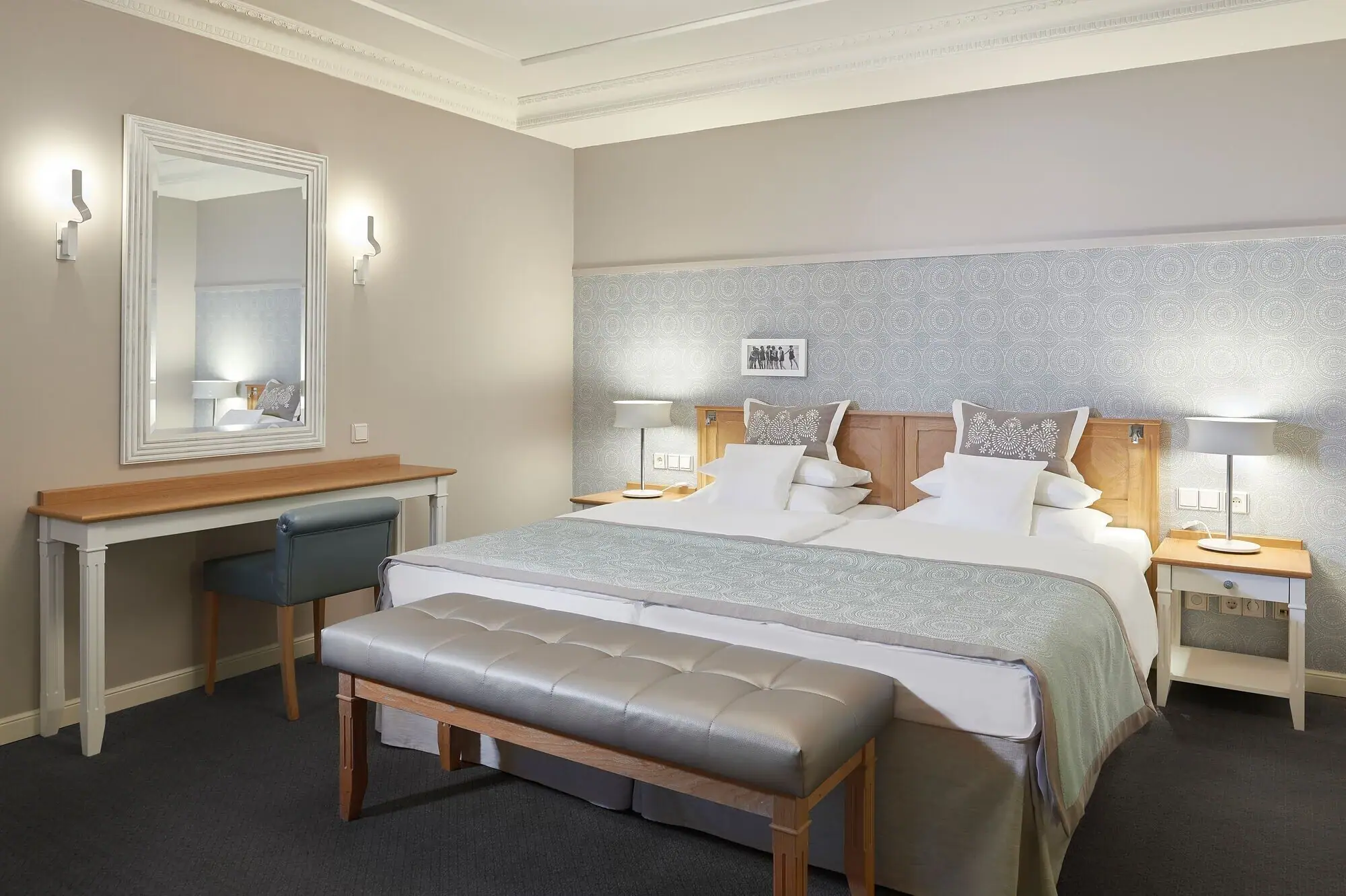 Hotelzimmer mit einem großen gemütlichen Bett und einem Spiegel an der Wand daneben.