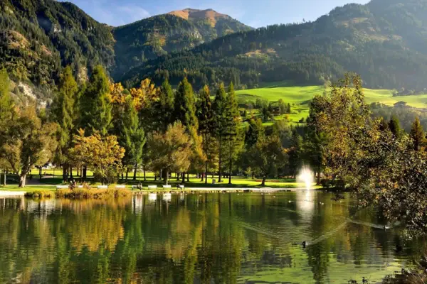 Eine grüne Landschaft mit Bergen und vielen Bäumen mit einem See im Vordergrund.