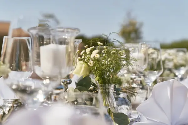 Elegant gedeckter Tisch mit Blumengestecken und Gläsern.