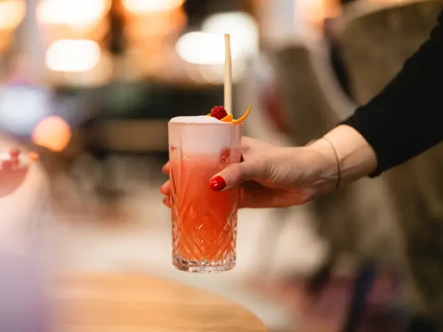 Eine Hand hält ein Glas mit einem Getränk.