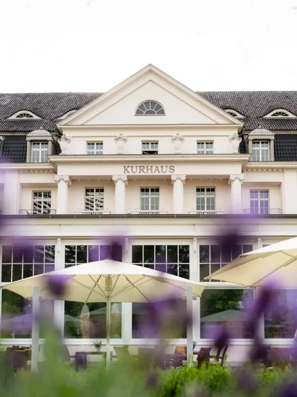 Ein Gebäude mit großen Fenstern, der Aufschrift "Kurhaus" und einem großen Sonnenschirm.