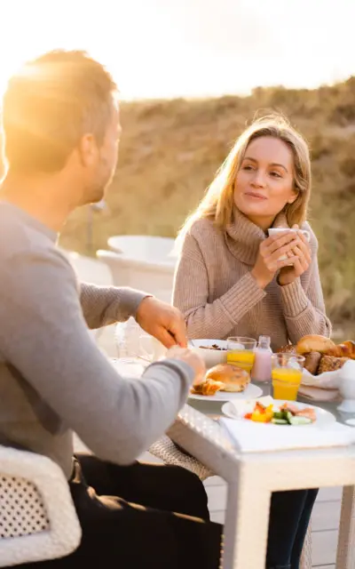 Ein Mann und eine Frau sitzen draußen an einem Tisch und essen.