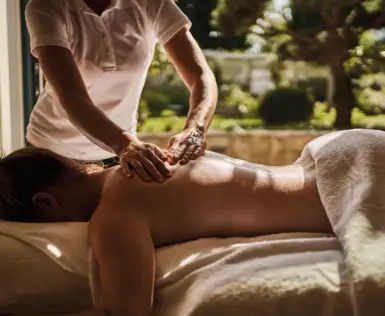 Eine Frau liegt auf einer Massageliege und bekommt ihren Rücken massiert.