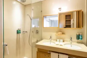 Badezimmer mit Dusche und Waschbecken, ausgestattet mit modernen Armaturen und Fliesen.