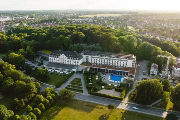 Das A-ROSA Travemünde mit Swimmingpool und umgebenden Bäumen.