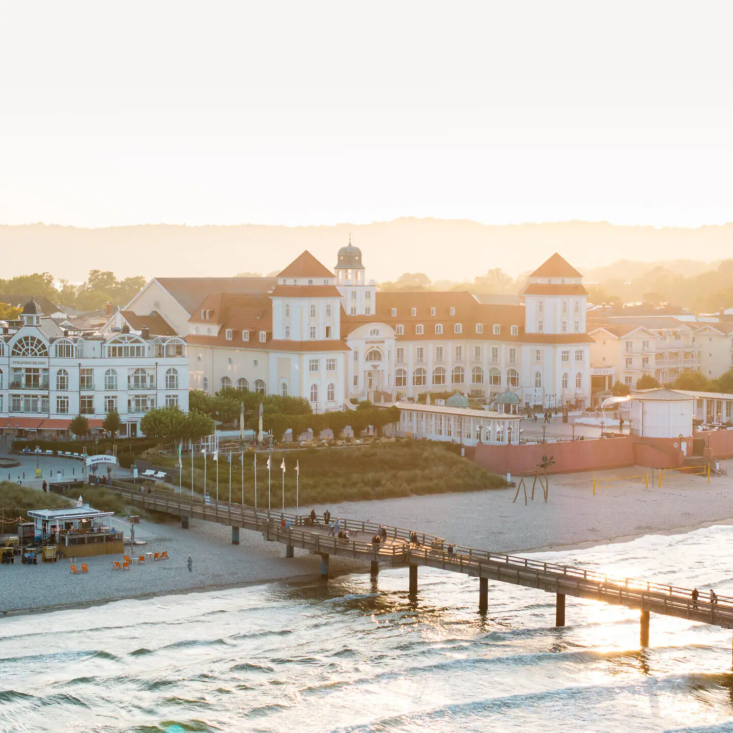 Ein Pier über einem Strand mit Gebäuden und einem Gewässer im Winter.