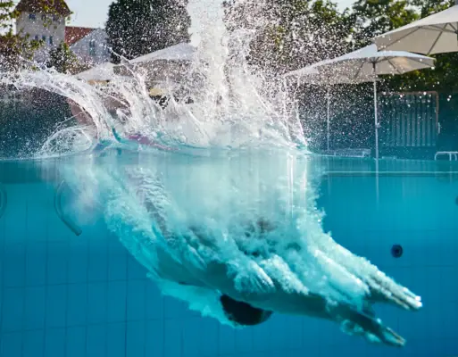 Eine Person taucht in einen Pool ein.