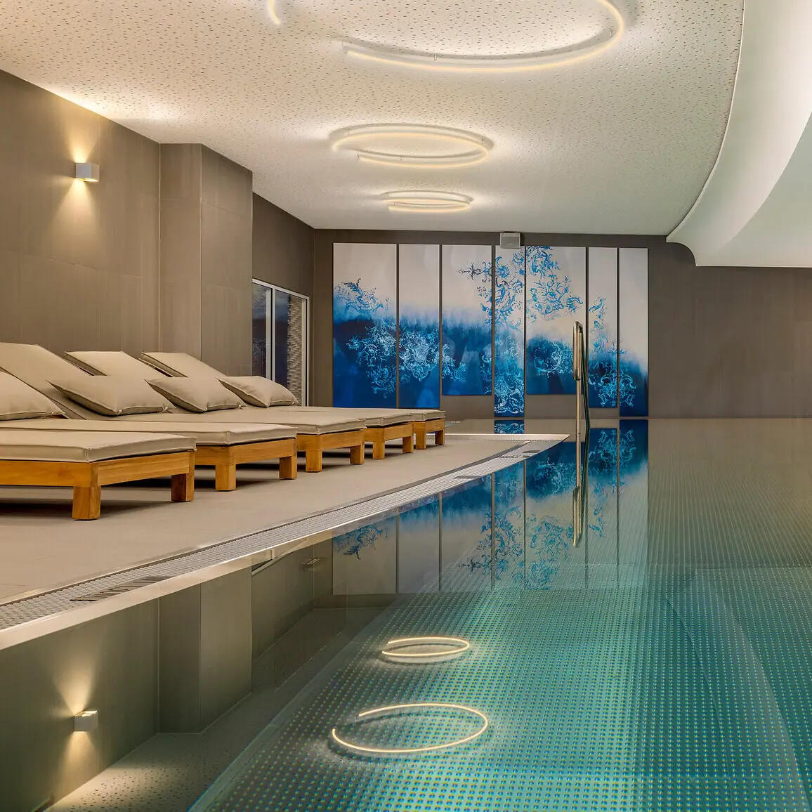 Ein Innenpool mit großer Terrasse und Liegestühlen.