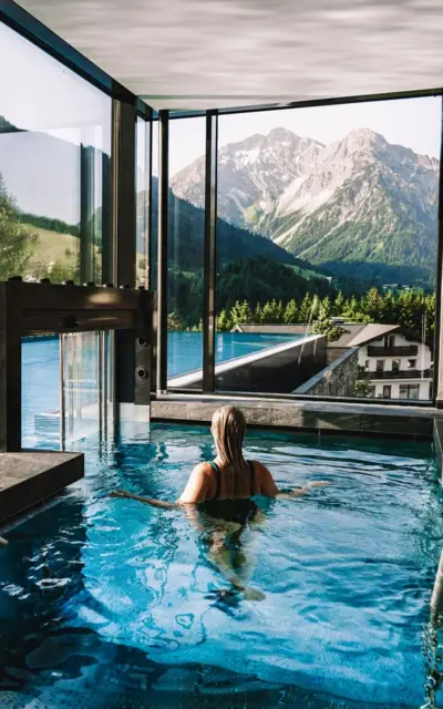 Woman swimming in a pool with a mountain backdrop.