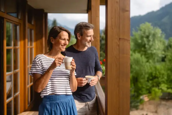 Mann und Frau halten Kaffeetassen auf einer Veranda.