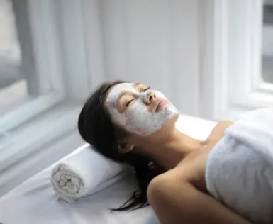 Eine Frau liegt mit einer weißen Maske auf dem Gesicht.
