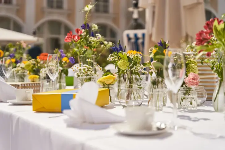 Ein heller Wintergarten mit vielen Tischen und einer Terrasse im Hintergrund.