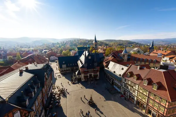 Stadtpanorama mit vielen Gebäuden, umgeben von Wolken und Bergen.