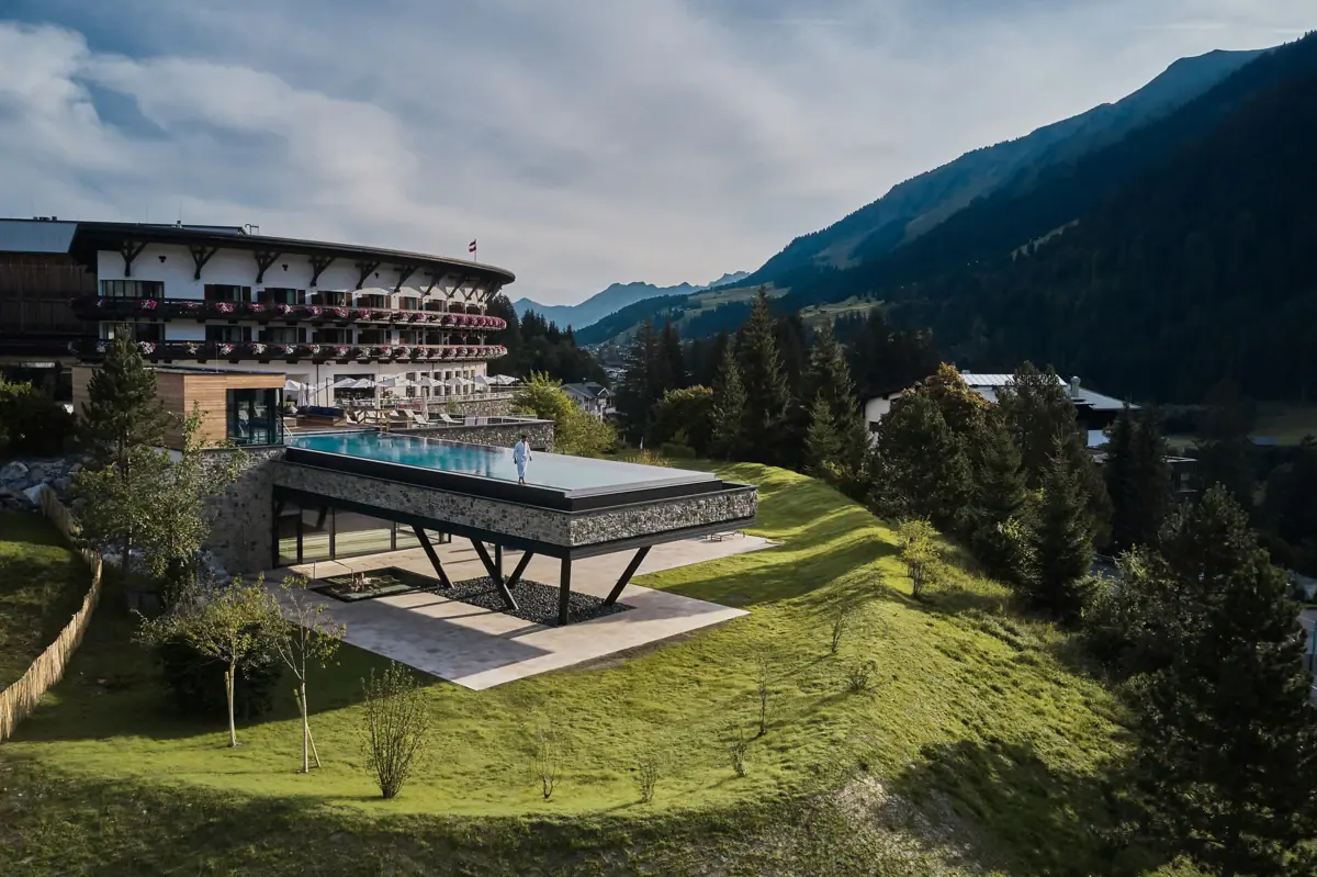 Ein Gebäude mit einem Pool in der Mitte, umgeben von Bergen und blauem Himmel.