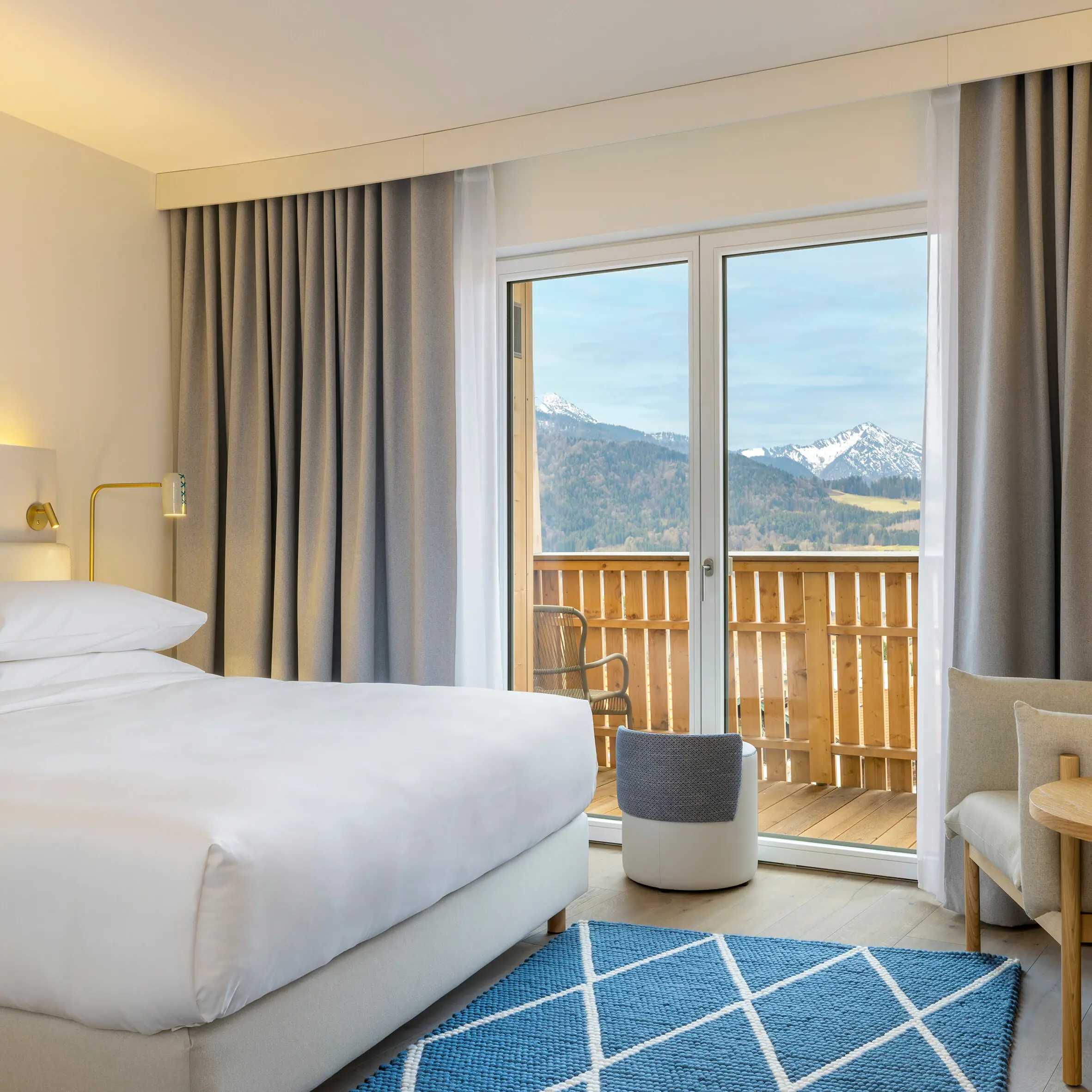 Ein Hotelzimmer im A-ROSA Tegernsee mit einem Bett, einem Sofa und einem kleinen Tisch.