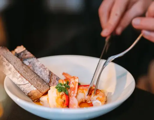 Eine Person hält eine Zange über eine Schüssel mit Essen.