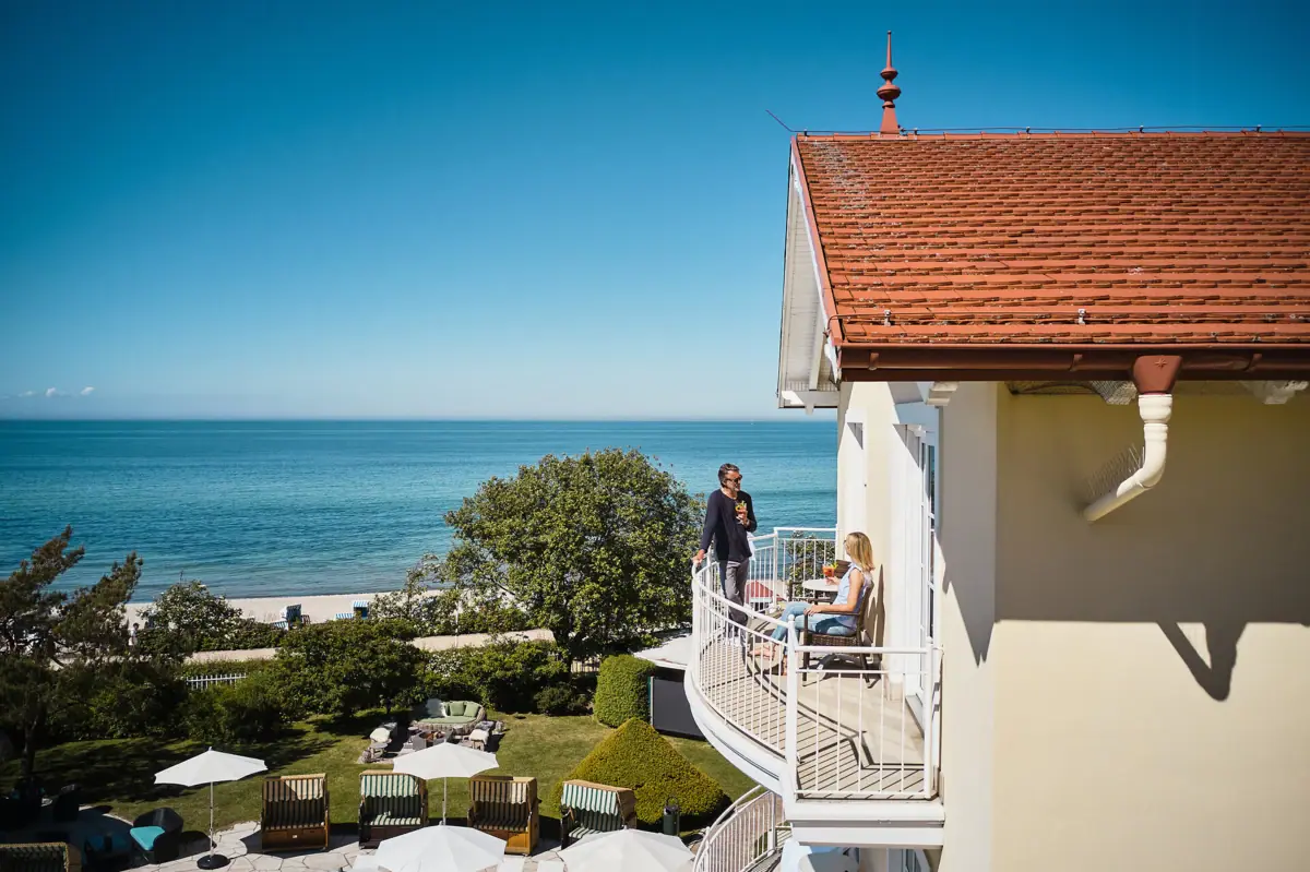 Ein Paar auf einem Balkon mit Blick auf einen Strand.