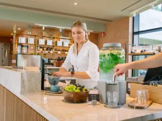 Frau gießt Tee in eine Tasse an der SPA-ROSA Rezeption.