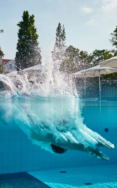 Person springt in einen Außenpool.